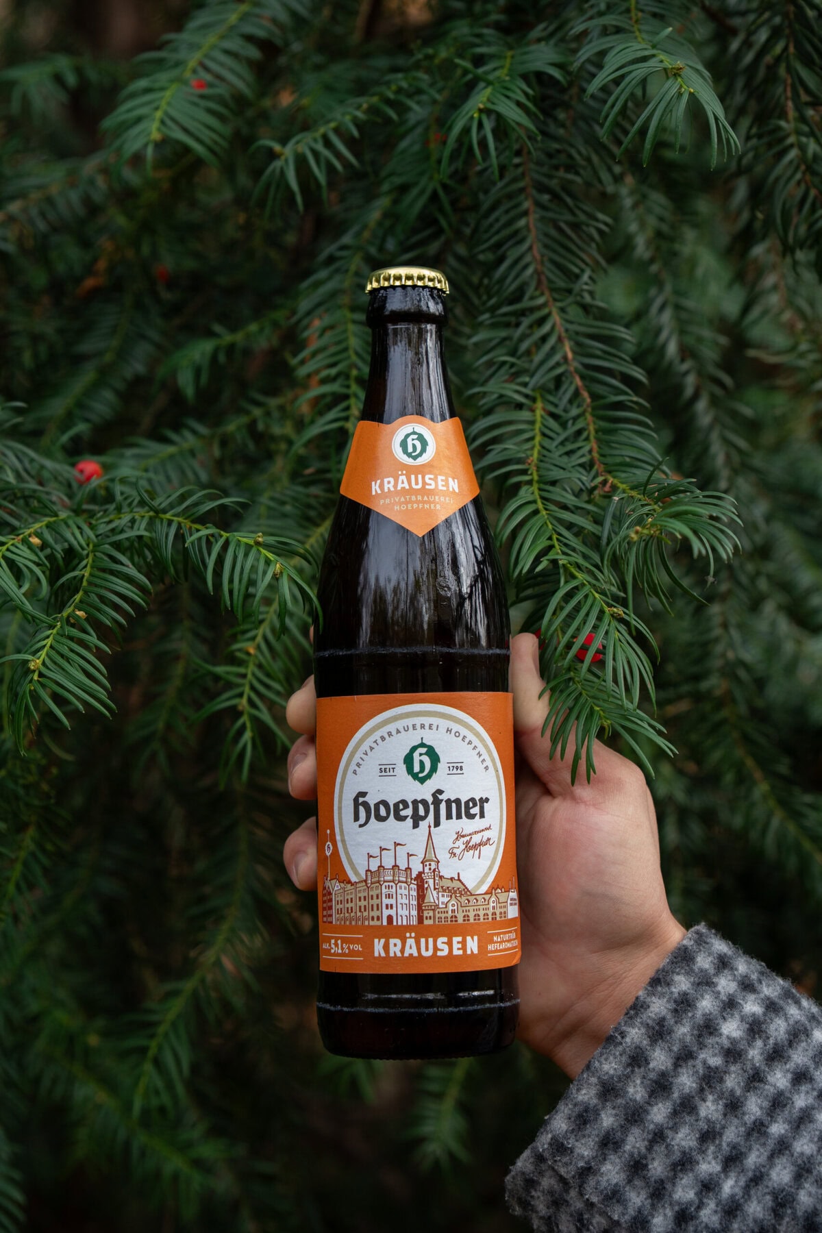 Flasche Kräuterbier von Hoepfner vor Tannenzweigen, saisonale Bierauswahl.