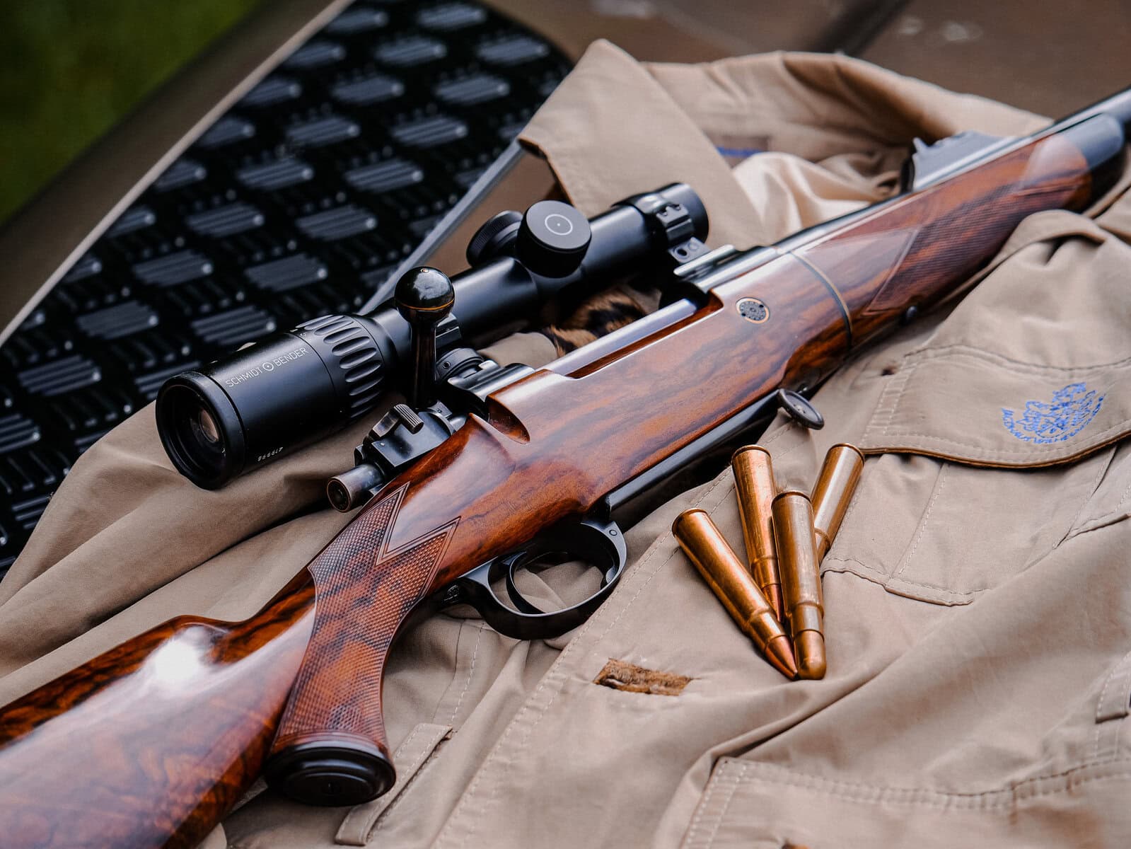 Jagdwaffe mit Zielfernrohr auf Jagdjacke, bereit für die Jagd im Wald.