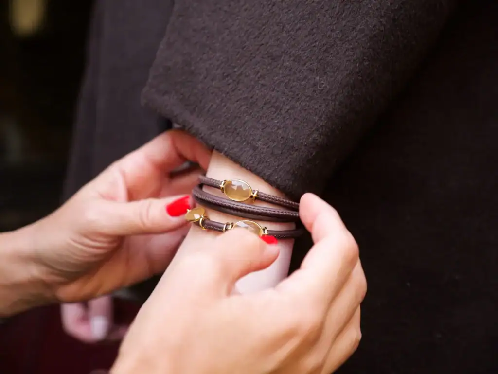 Nahaufnahme einer Hand, die Armbänder an einem dunklen Mantel befestigt.